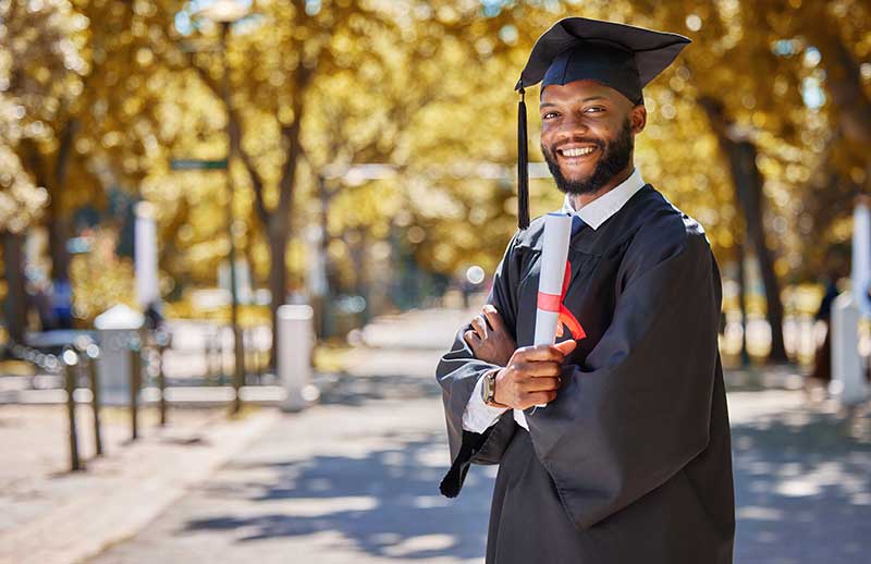Man in college graduation degree, holding a degree