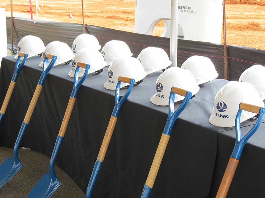 Hard hats with the GTR Link logo on them lined up next to blue shovels at a site